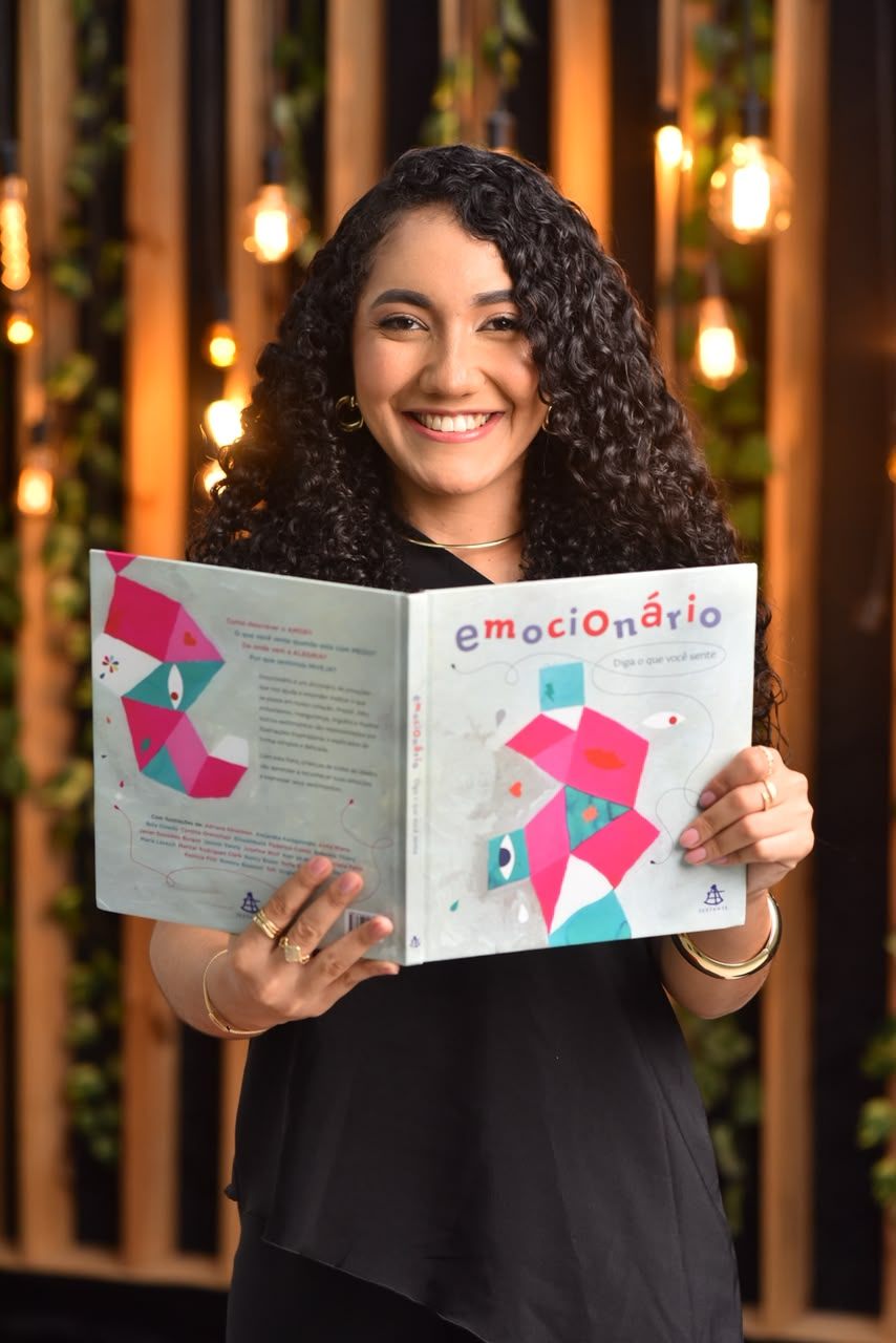 Valéria Carneiro segurando o livro Emocionário